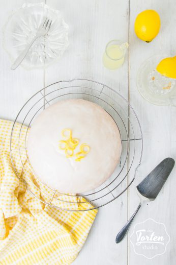 Veganer Zitronenkuchen auf einem Kuchengitter mit Tortenheber
