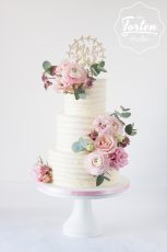 dreistöckige Hochzeitstorte mit Buttercreme in Streifenoptik, dekoriert mit Ranunkel, Rosen und Lisianthus in Blush und Rosa
