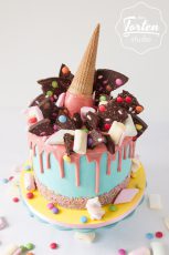 Türkise Buttercreme-Torte mit rosa Schokodrip, dekoriert mit Marshmellwos, Schokosplitter, Smarties, Streusel und Eistüte