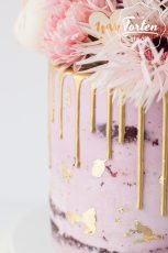 Detailaufnahme von Rosa Semi Naked Cake mit goldenem Drip, Blattgold, einem Happy Birtday Topper und üppiger Blumendeko