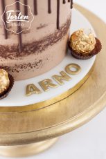 Schokolade-Semi Naked Cake mit Schokodrip, dekoriert mit Ferrero Rocher + Name "Arno" in Goldbuchstaben