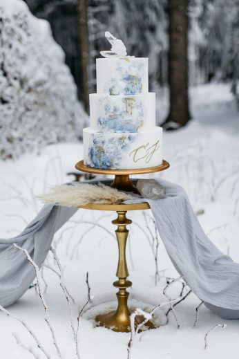 dreistöckige Hochzeitstorte dekoriert mit einem gemalten, blauen Wasserfall in Watercolour Technik und Zuckerkristallen, mit goldenen Akzenten, Winterhochzeit