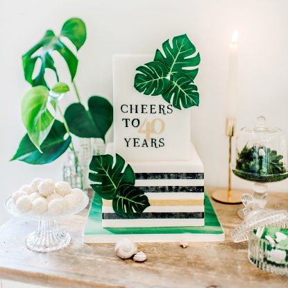 Zweistöckige Geburtstagstorte, rechteckig, dekoriert mit Streifen, grünen Blättern und einer Aufschrift