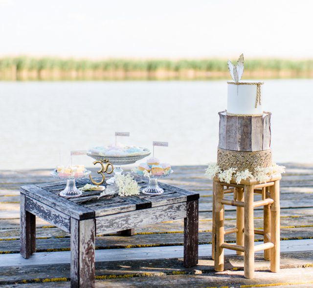 Zweistöckige Hochzeitstorte im Boho Stil auf einem Stockerl am Seeufer