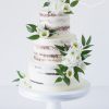Dreistöckiger Semi Naked Cake, dekoriert mit kleinen weißen Blüten und Ruskus