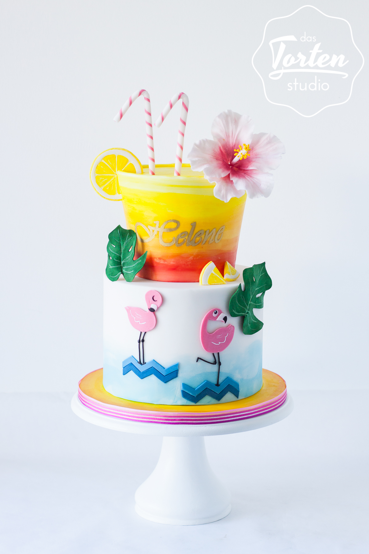 Zweistöckige Geburtstagstorte mit Flamingos, Cocktail und einer Hibiskusblüte aus Zucker