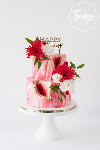 Zweistöckige Torte mit rot-weiß marmoriertem Fondant überzogen, dekoriert mit echten Blumen