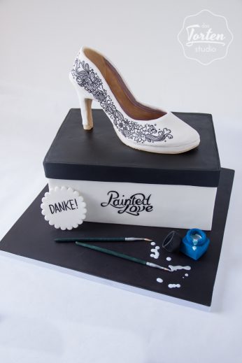 Torte in Form einer Schuhschachtel, dekoriert mit einem Zuckerschuh, Pinsel und Tintenglas