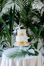 Zweistöckige weiße Torte, Gold gemalt am Fuß der Etagen, weiße Zuckerblumen